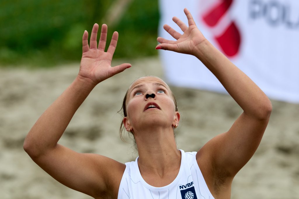 En kvinnelig sandvolleyballspiller ser opp mens hun forbereder seg på å sprette ballen.