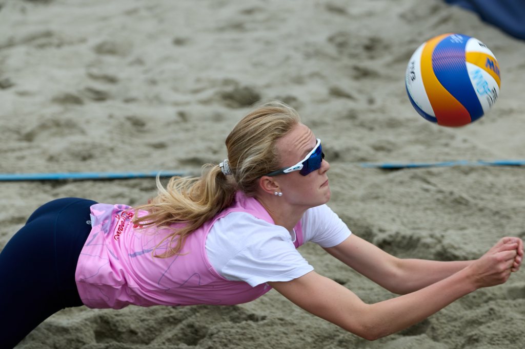 En beachvolleyballspiller som dykker etter ballen på sanden.