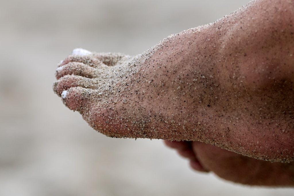 En fot dekket med sand, sett fra siden, med fokus på tærne.