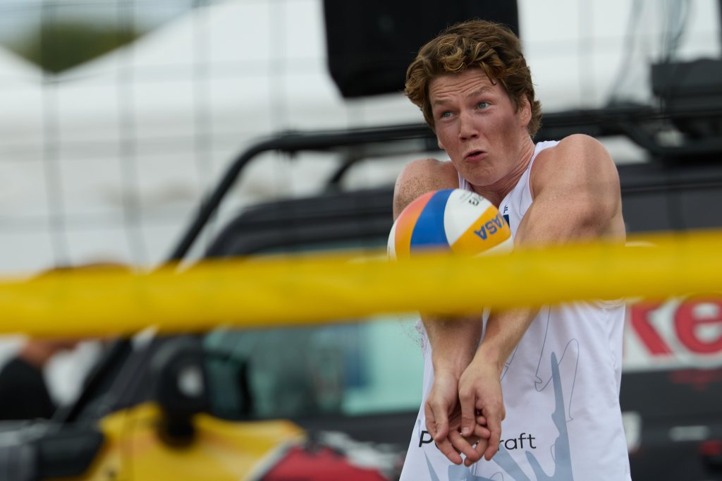 En volleyballspiller i aksjon, som forsøker å motta en ball under en kamp på stranden.