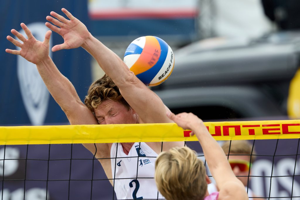 En volleyballspiller prøver å blokkere en ball som kommer mot nettet under en kamp.
