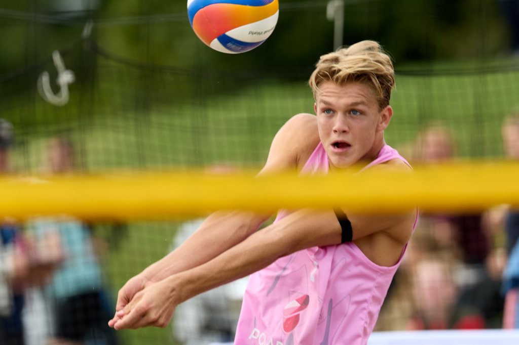Ung spiller i rosa drakt som prøver å ta imot en volleyball under en kamp.