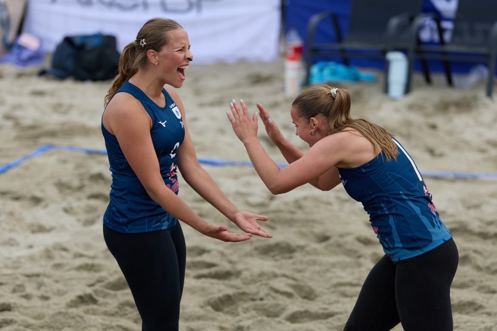 To kvinnelige volleyballspillere jubler og feirer på sandbanen.